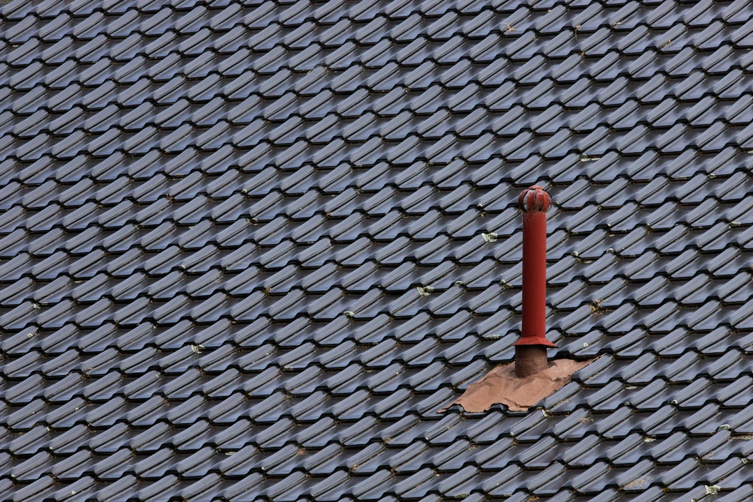 Split-roof home showing architectural asphalt shingles on one side and standing-seam metal roof on the other