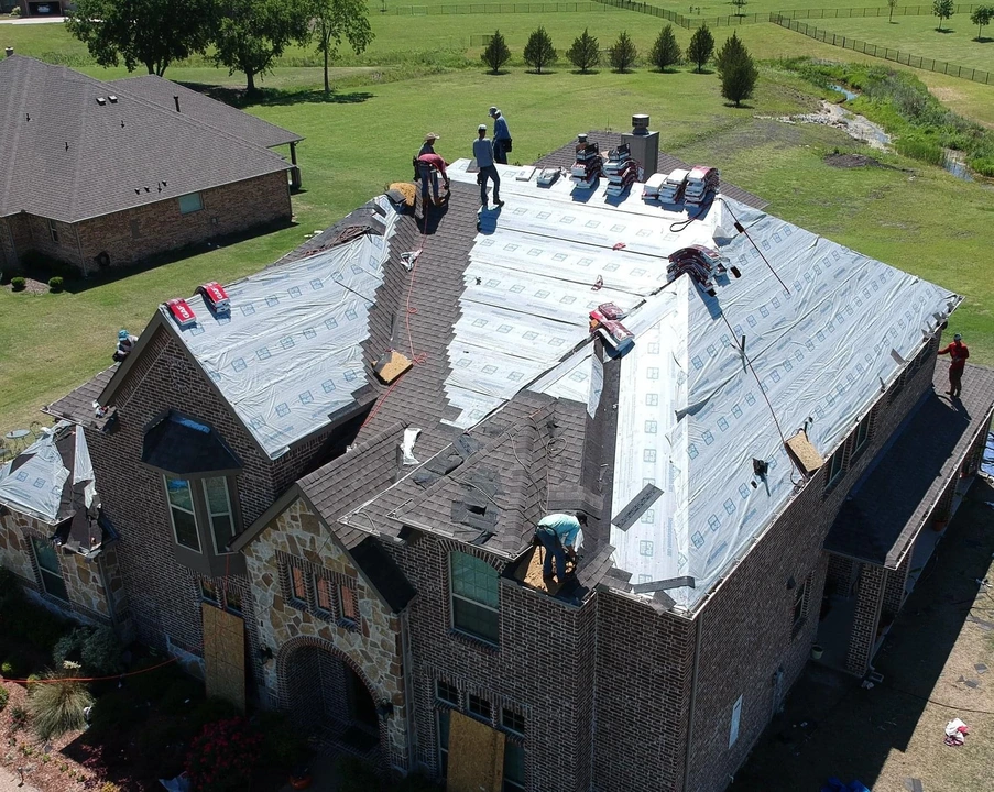 Roofing contractor on roof examining shingles, representing repair vs replacement decision-making process